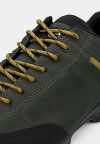 Dark green suede shoe with yellow laces, black toe cap, and rubber sole. Features stitching and metal eyelets for laces.