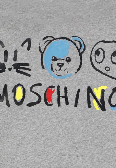 Disegni di volti di gatto, orso blu e nero e volto dagli occhi tondi sopra il testo stilizzato e colorato "MOSCHINO" su un tessuto grigio.