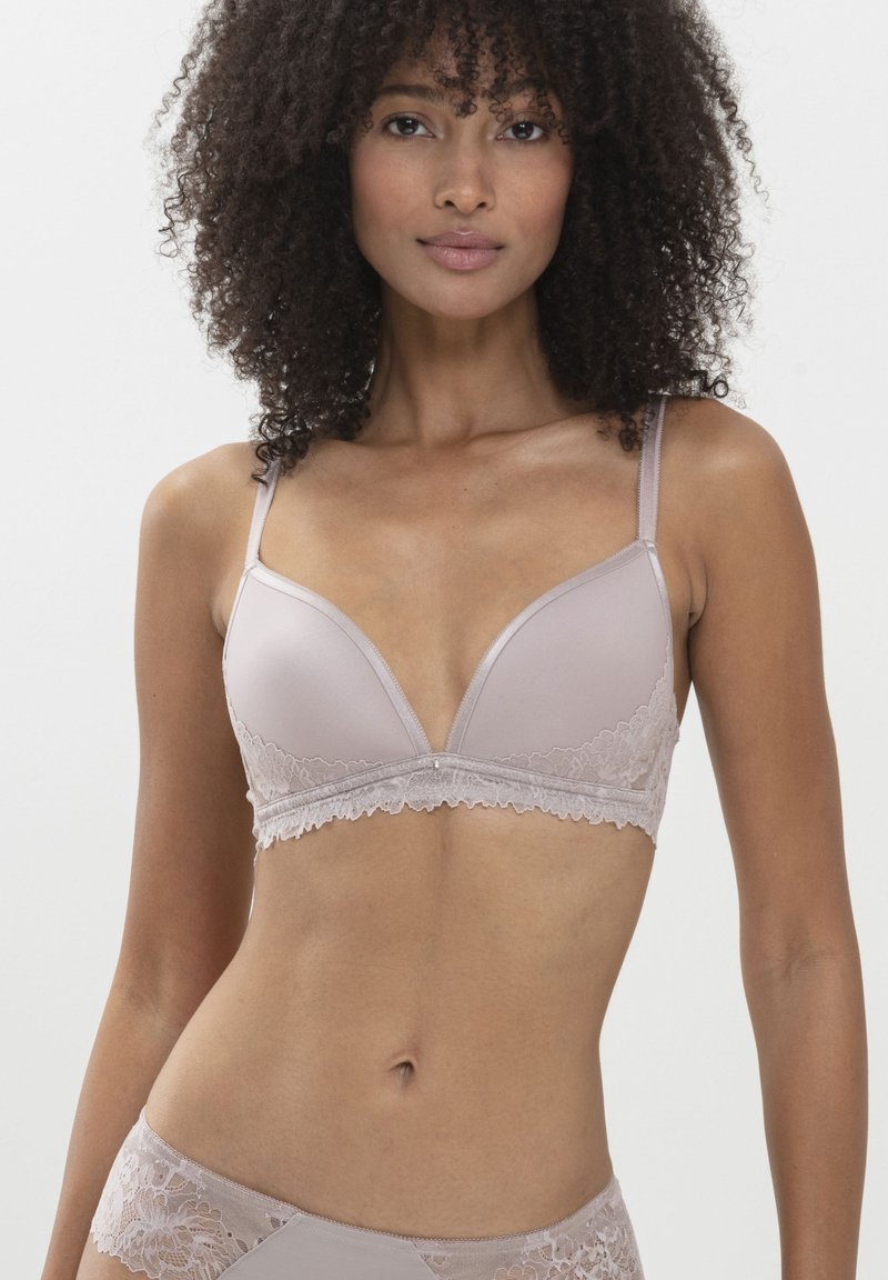 Beżowy stanik zdobiony koronką, z gładkim satynowym wykończeniem, trójkątnymi miseczkami i regulowanymi ramiączkami. Zawiera subtelną dekoracyjną akcentację na środku.