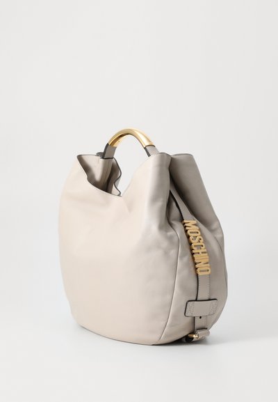 Beige leather handbag with a sleek shape, gold hardware, a curved handle, and a side strap featuring the brand name in gold lettering.