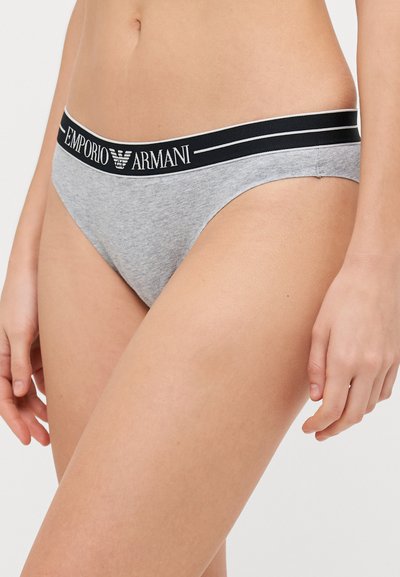 Zila kokvilnas bikiniers ar melnu jostu. Josta ir ar baltu uzrakstu "Emporio Armani." Gluda tekstūra, minimālistisks dizains.
