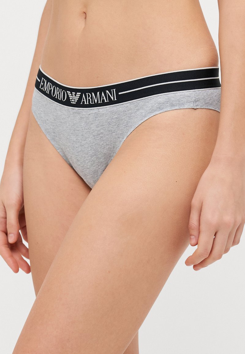 Bikini en coton gris avec une taille noire. La taille présente des lettres blanches indiquant "Emporio Armani". Texture lisse, design minimal.
