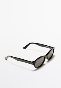 Occhiali da sole neri con montatura audace e arrotondata, lenti scure e finitura liscia e lucida. Presentano un design elegante e aste curve.