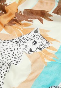 Écharpe légère présentant un motif léopard imprimé en noir et blanc, entouré de formes abstraites dans des teintes orange et turquoise.