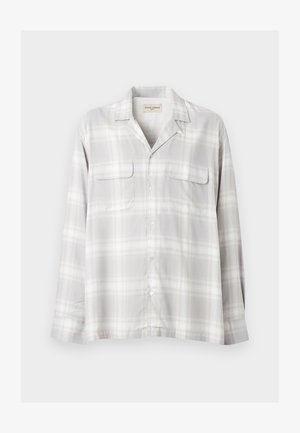 Chemise à manches longues boutonnée avec motif à carreaux gris clair et blanc et deux poches poitrine sur fond uni.