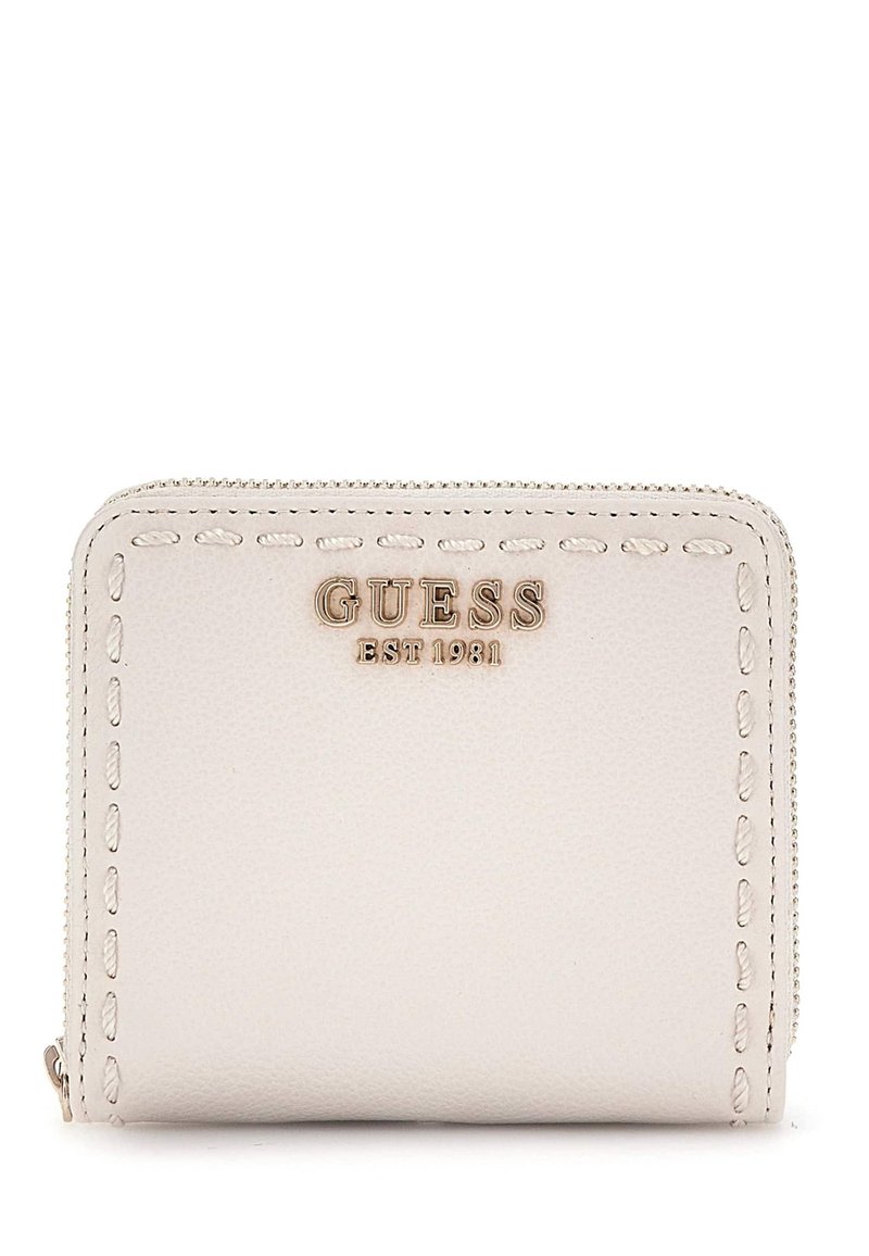 Portefeuille en cuir beige avec des bords cousus, logo doré "GUESS EST. 1981" à l'avant, fermeture zippée, forme carrée compacte.