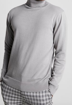 Grauer Rollkragenpullover mit langen Ärmeln, gerippten Bündchen und Saum, aus einem glatten, leichten Material gefertigt, kombiniert mit karierten Hosen.