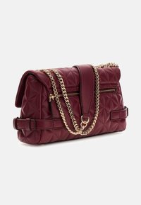 Borsa trapuntata color bordeaux con tracolla a catena dorata e manico piatto per la spalla. Presenta una chiusura a pattina e una tasca posteriore con cerniera.