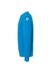 Sweatshirt bleu clair à manches longues avec un col rond, présenté de côté, arborant un logo circulaire blanc avec la lettre K sur la manche.