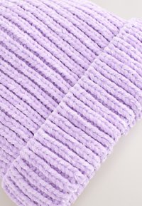 Lilla strikket hue med ribbet tekstur. Fremstillet af blødt stof, den har tydelige vandrette linjer og en opslået kant.