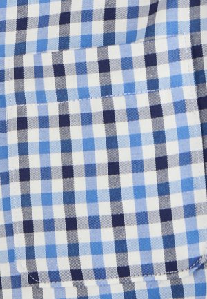 Tessuto a scacchi blu e bianco con piccoli quadrati di diverse tonalità di blu, con un dettaglio tasca. La texture appare liscia.