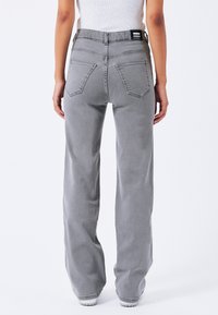 Grijze high-waisted jeans met een relaxte pasvorm, met achterzakken, stikseldetails en een merklabel bij de tailleband.