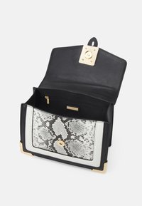 Czarna torebka ze sztucznej skóry z przednią częścią w wzór węża, złotymi zdobieniami i zamykaną na zamek kieszonką wewnątrz. Kwadratowy kształt z białymi akcentami.