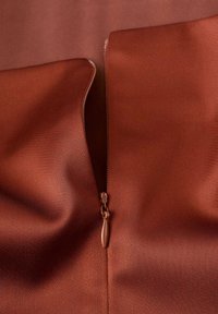 Tela de satén marrón con una textura suave, con un zipper visible en un tono marrón a juego en el centro.