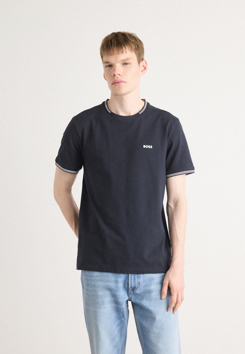 Tamsiai mėlynas apvalios iškirptės marškinėliai, pagaminti iš medvilnės, su balta apykaklės ir rankovių apdaila, su mažu baltu "BOSS" logotipu krūtinėje.