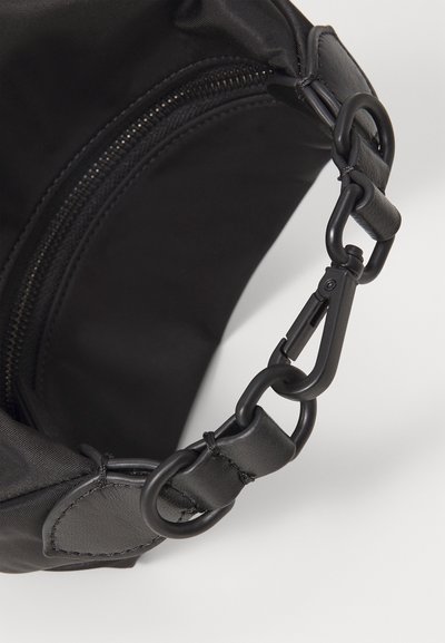 Mustmust kott, millel on tõmbluku sulgemine, nahast rihm ja metallist tarvikud, sealhulgas klamber ja tugevdusõmblused.