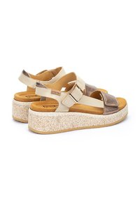 Sandalias de plataforma beige y marrón con correas ajustables, suelas texturizadas y una cuña moteada. Materiales de suave ante y cuero utilizados.