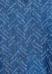 Blått texturerat denimtyg med ett zigzagmönster, med varierande nyanser av blått som skapar djup och visuellt intresse.