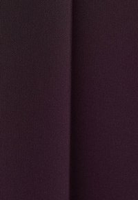 Gros plan d'un tissu violet foncé montrant une texture fine tricotée avec une couture verticale au centre.