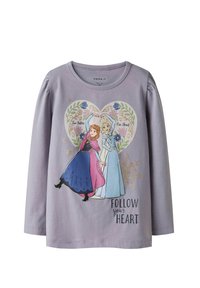 Liliowa koszula z długim rękawem z grafiką dwóch sióstr w kolorowych sukienkach, otoczonych kwiatowymi wzorami i napisem "PODĄŻAJ ZA SWOIM SERCEM".