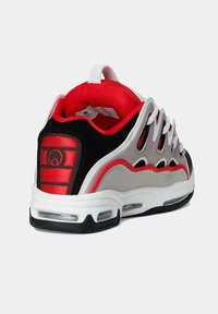 Zapatilla deportiva roja, negra, gris y blanca con suela acolchada, bolsillos de aire visibles, cordones blancos y forro interior acolchado rojo.