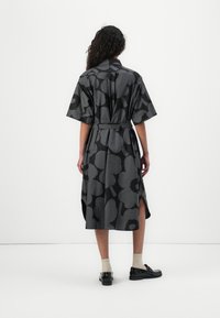 Black floral print dress with short sleeves, belted waist, and side slits. Smooth texture and knee-length design. Flat black shoes and beige socks.