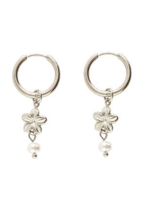 Pendientes de aro de plata con colgantes de flores de cinco pétalos y pequeñas perlas blancas debajo de las flores sobre un fondo blanco.