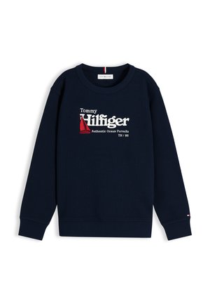 Sweat-shirt bleu marine Tommy Hilfiger avec logo blanc et rouge marqué "Authentic Ocean Pursuits" et un motif de voilier rouge sur la poitrine.