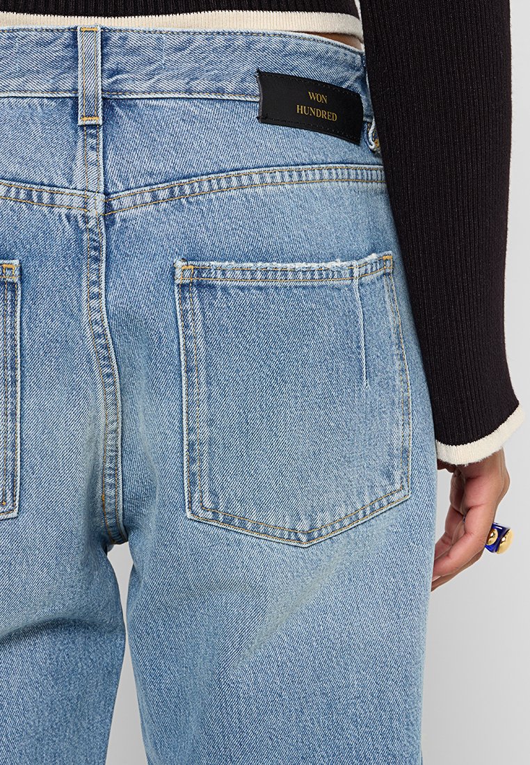 Hellblaue Denim-Jeans mit einer hochgeschnittenen Passform. Verfügt über große Gesäßtaschen und ein schwarzes Markenlabel. Glatte Textur mit Ausbleichungen.