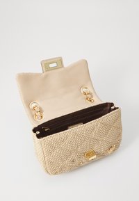 Beige vevd clutchveske med teksturert finish, detaljer i gull, og trykknap-lukking; innsiden har en brun stoffforing og en glidelåslomme.