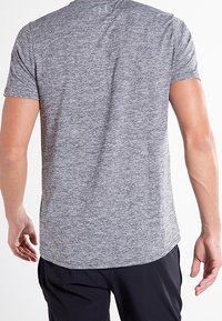 Grå kortärmad sportt-shirt, melange-textur, rundad nederdel och en åtsittande passform. Märkeslogotyp nära nacken.