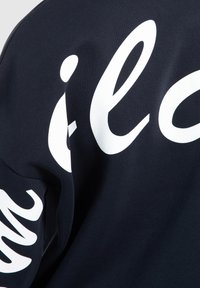 Sudadera azul marino con gran texto blanco en la manga izquierda y en la parte posterior. Tejido de algodón con una textura suave. Diseño de corte relajado.