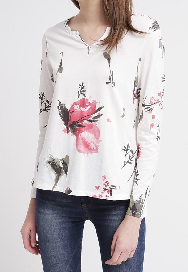 Långärmad vit skjorta med blommönster i rosa, grönt och svart. V-ringning, mjukt tyg, avslappnad passform och lätt textur.