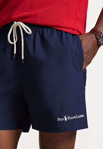 Ναυτικά μαγιό κολύμβησης κατασκευασμένα από ελαφρύ ύφασμα με ελαστική μέση και λευκή κορδόνι· διαθέτουν λευκό κεντητό λογότυπο στο τελείωμα.