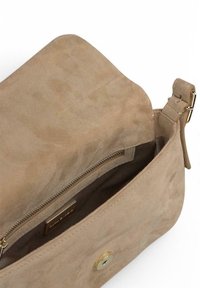 Bolso de suède beige con una textura suave, que presenta un cierre de cremallera dorada y botón. El interior cuenta con un forro de tela.