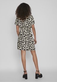 Robe imprimé léopard à manches courtes, détail avec lien à la taille, ourlet à hauteur du genou, et sandales noires à talons hauts. Tissu doux avec une texture lisse.