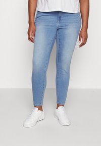Jeans skinny de un albastru deschis, din țesătură de denim, având un design ajustat, talie standard și croială până la gleznă, asortați cu adidași albi.
