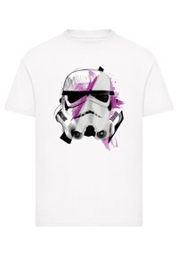 Weißes T-Shirt mit einem grafischen Design eines Stormtrooper-Helms in Schwarz und Pink, ergänzt durch abstrakte Pinselstrich-Akzente.