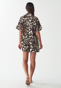 Kort klänning med leopardmönster och korta ärmar, med två fickor framtill. Tillverkad av mjukt tyg med en lös passform.