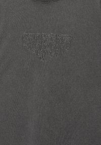 Schwarzgraues Baumwoll-T-Shirt mit einem strukturierten, kontrastierenden, gestickten Design auf der Brust, rundem Halsausschnitt und kurzen Ärmeln.