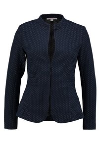 Granatowa kurtka z długimi rękawami, okrągłym dekoltem i zapięciem z przodu. Posiada biały, kropkowany wzór oraz dwie przednie kieszenie. Gładka tekstura.