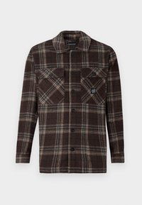 Bruine geruite button-up overhemdjas met twee voorzakken met knopen op de borst en een klein logo-opdracht op de rechterszak.