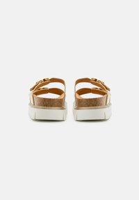 Brown and gold sandals with a cork base, white platform sole, and adjustable strap featuring a gold buckle. Lightweight and open-back design.