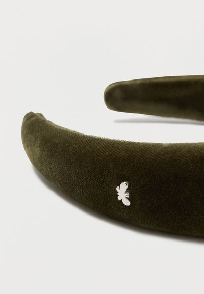Diadema de terciopelo verde oliva con una textura suave, que presenta un pequeño acento de mariposa plateada en el lateral. Diseño curvado para un ajuste cómodo.