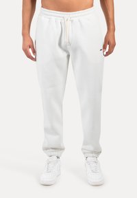 Weiße Jogginghosen aus weichem Stoff mit elastischem Bund und Bündchen. Verfügen über Seitentaschen und ein dezentes Logo an der Hüfte.