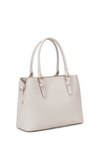 Borsa a mano beige chiaro realizzata in materiale testurizzato. Presenta manici doppi, accessori in oro e una chiusura con zip dal design minimalista.