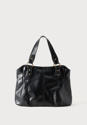 Sac à épaule en cuir noir avec double anses attachées par des anneaux et rivets dorés, surface lisse et légèrement brillante, design simple.