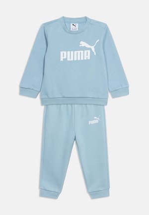 Chándal infantil Puma azul claro con camiseta de manga larga y pantalones con cintura elástica, con el logo blanco de Puma en el pecho y el muslo.