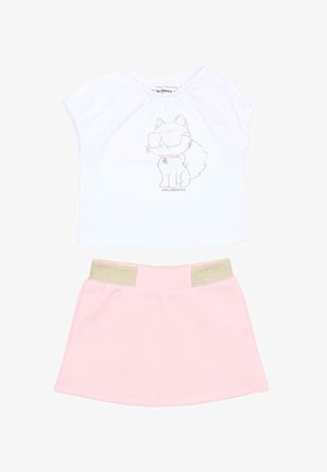 Haut blanc à manches courtes avec un chat de dessin animé portant des lunettes de soleil, associé à une jupe rose avec une taille élastique dorée.