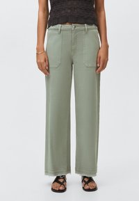 Ljust gröna vida byxor i bomull, med två framfickor, fransad fåll och knappstängning. Matchas med svarta sandaler.